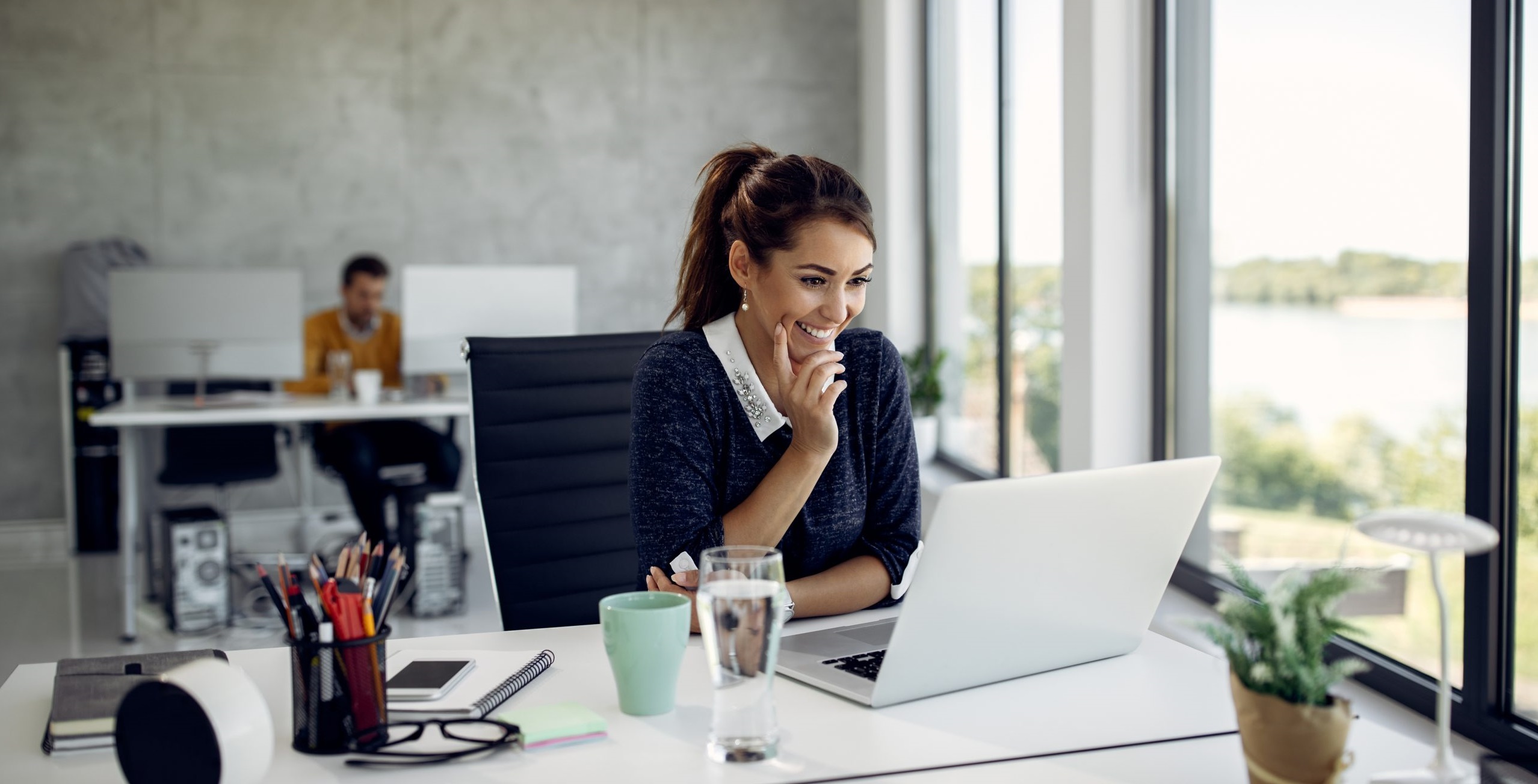 1-happy-businesswoman-reading-something-internet-while-using-computer-office-scaled